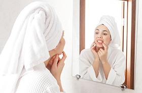 Woman looking at her mouth in bathroom mirror