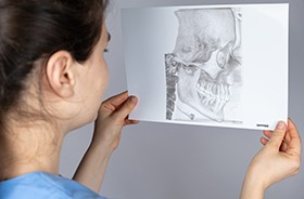 Dentist looking at printout of patient’s jaw scan