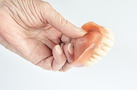 Senior person’s hand holding upper dentures