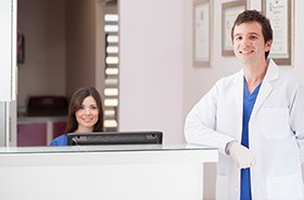 Dentist standing next to front office desk