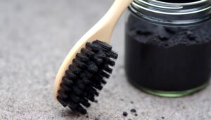 Toothbrush next to small jar of activated charcoal