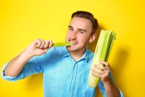 Handsome man eating celery